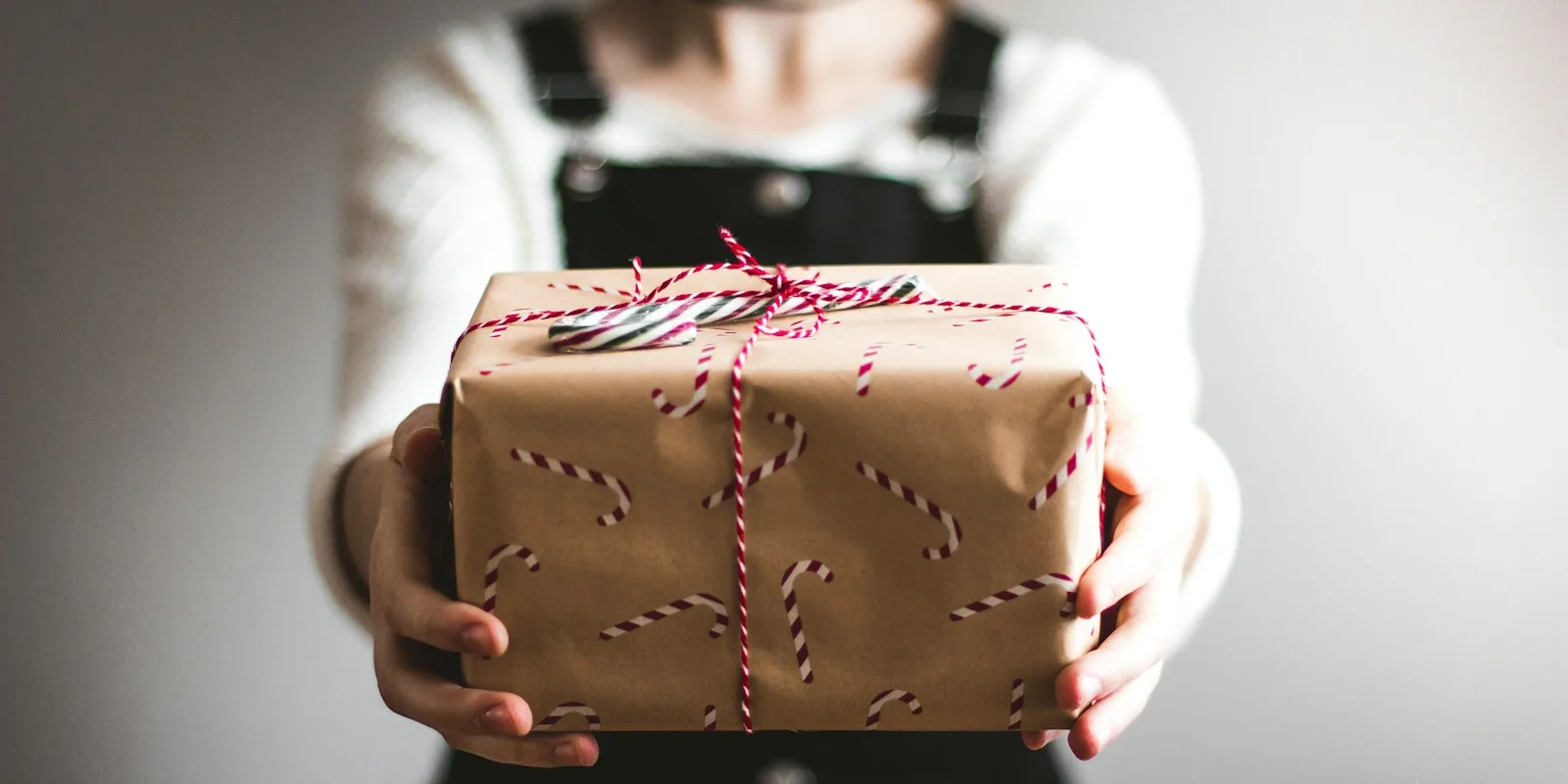 Customer retention in e-commerce: hands holding out a wrapped parcel with a ribbon